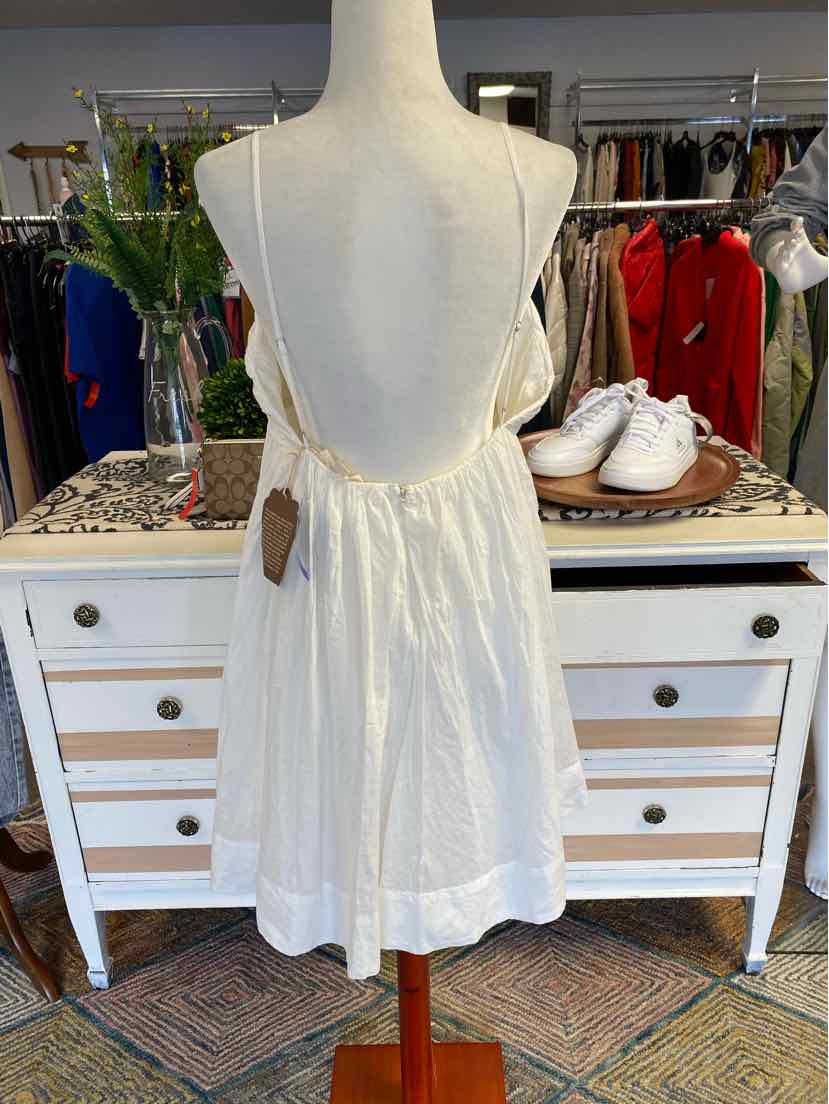White sleeveless summer dress with low back and thin spaghetti straps on mannequin.