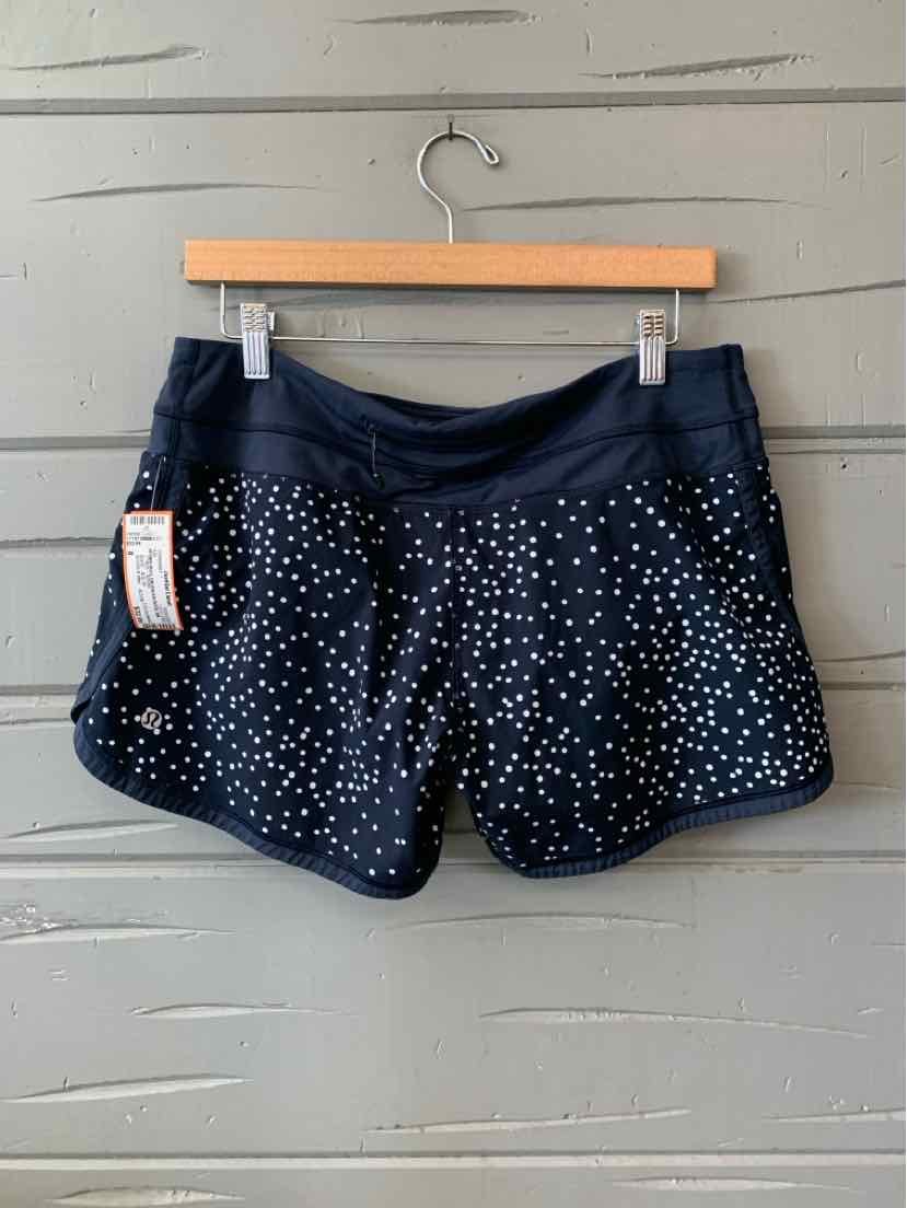 Black athletic shorts with white polka dots, wide waistband, and curved hem, size 8.