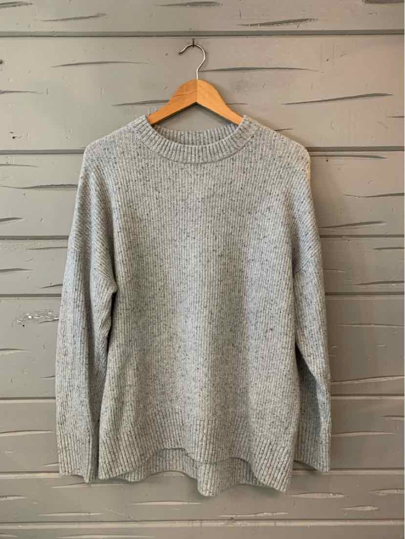 Light gray knit sweater with long sleeves and ribbed crew neckline, cuffs, and hem, hanging on wooden hanger.