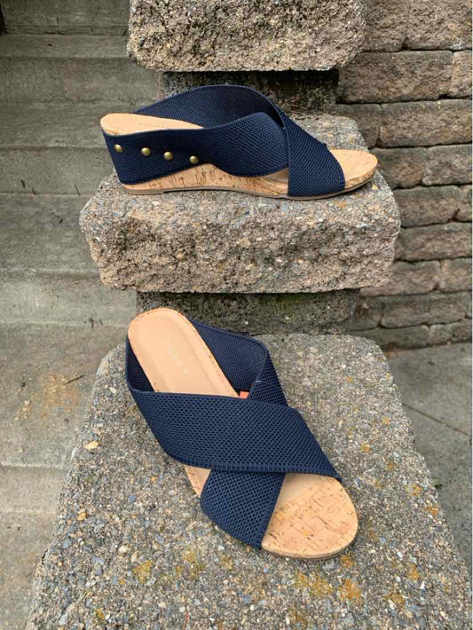 Navy blue crisscross fabric straps sandal with tan cork wedge heel and gold stud accents.