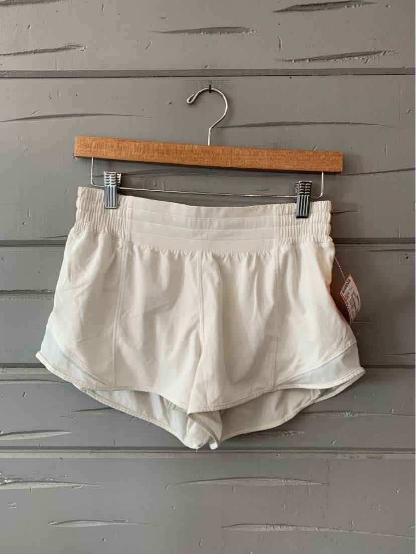 Light beige athletic shorts with elastic waistband and curved hem, lightweight fabric.