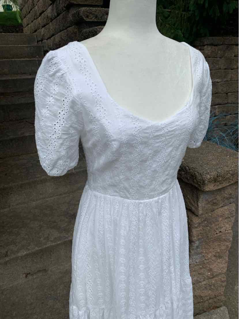White eyelet lace dress with fitted bodice, puff sleeves, and scoop neckline.