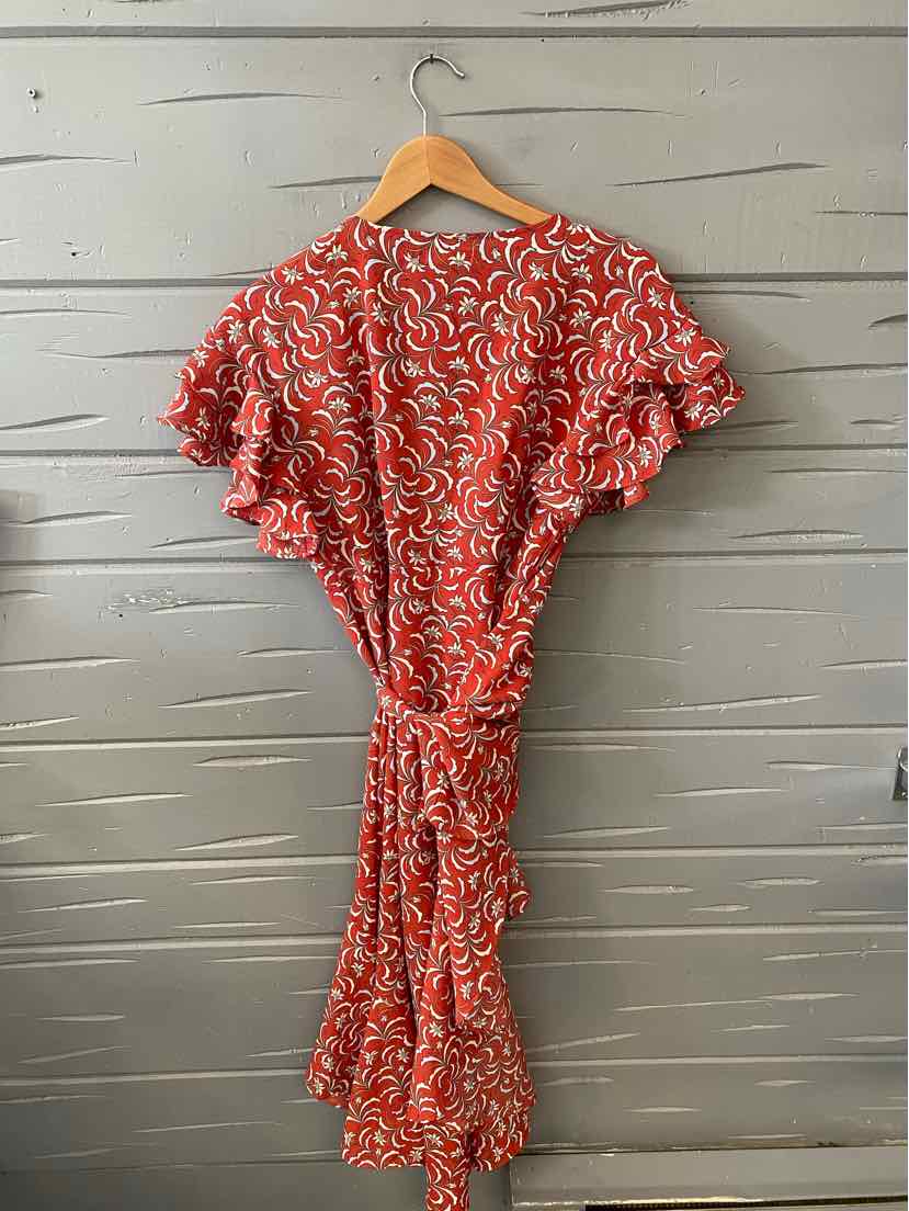 Red short-sleeve dress with white abstract pattern and gathered waist on wooden hanger.