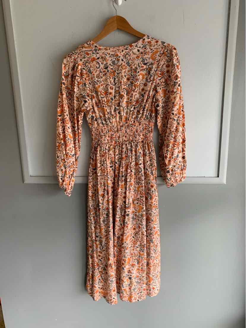 Orange floral midi dress with long sleeves and cinched waist hanging on wooden hanger.