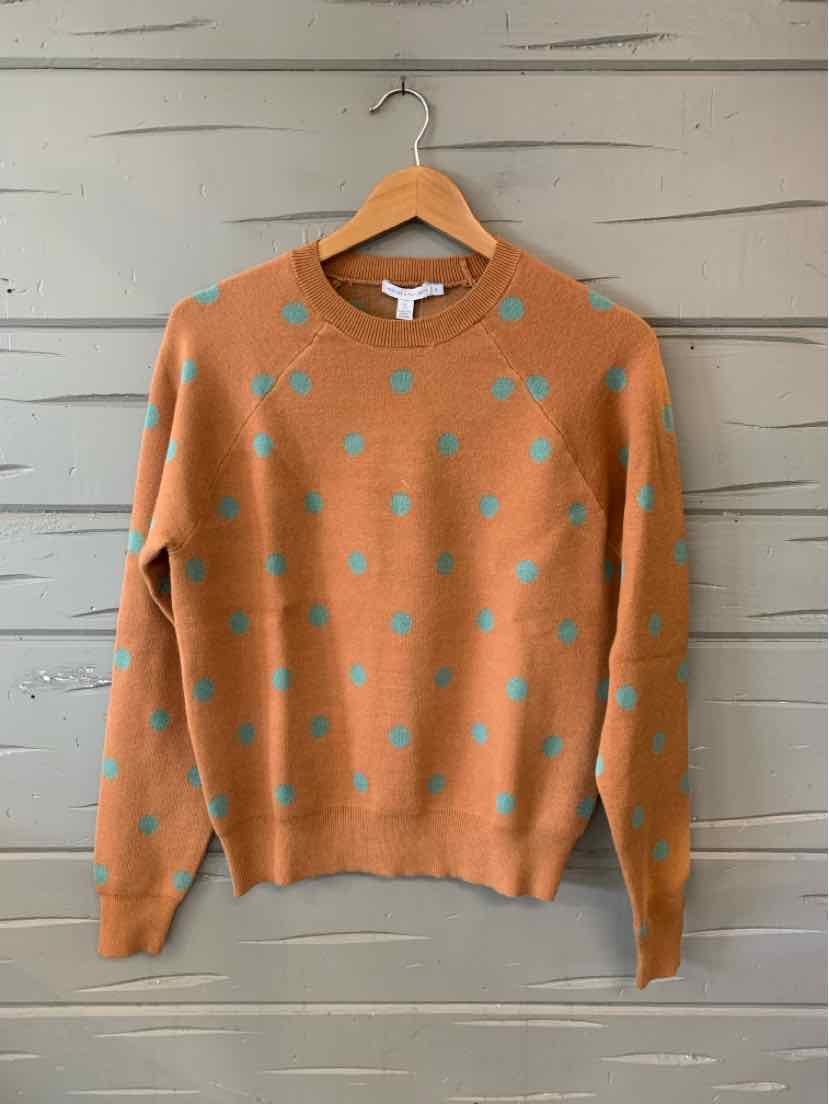 Light brown crewneck sweater with turquoise polka dots, long sleeves, ribbed cuffs and hem, hanging on wooden hanger.