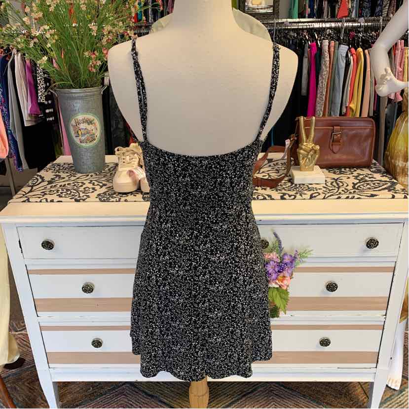 Black spaghetti strap mini dress with white floral print and fitted waist.
