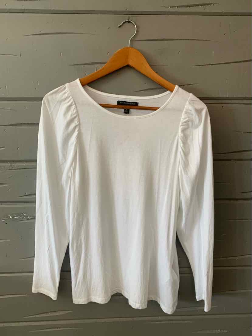 White long-sleeve shirt with slight puff shoulders and scoop neckline on wooden hanger.