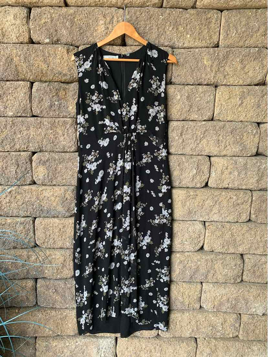 Black sleeveless midi dress with white floral print and deep V-neckline on wooden hanger.