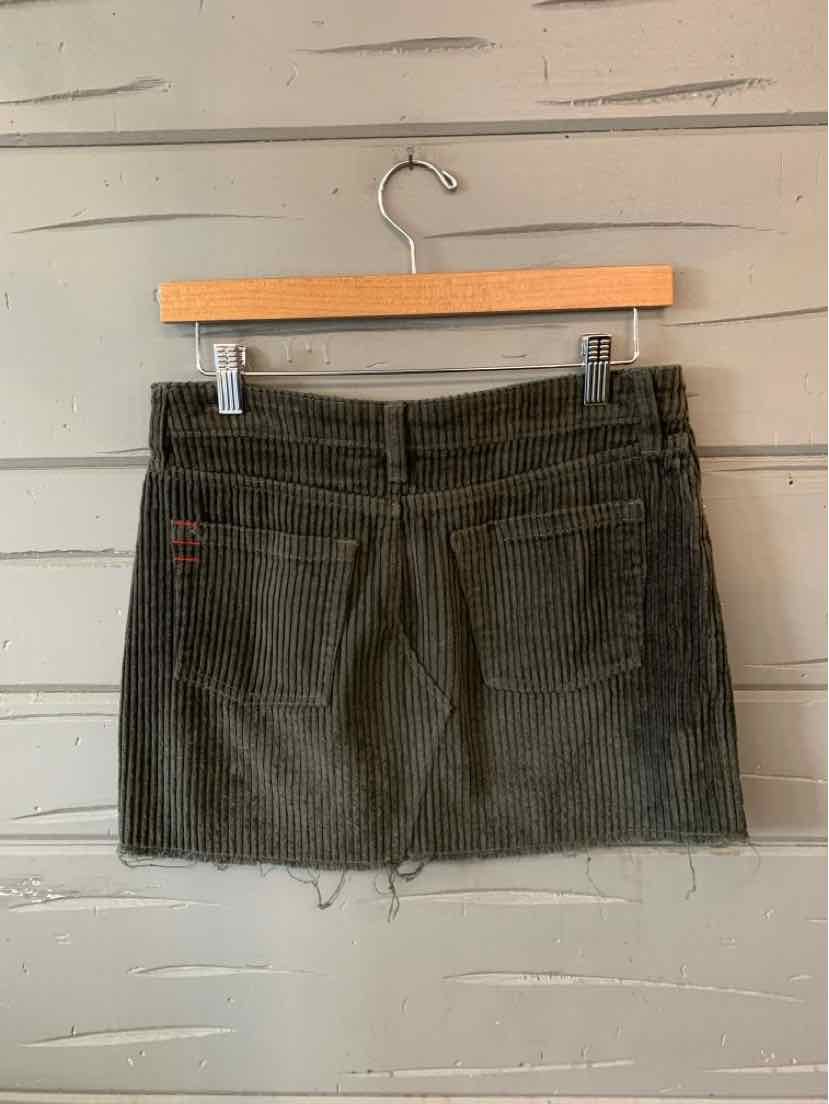 Dark gray corduroy mini skirt with front pockets and drawstring waist on wooden hanger.