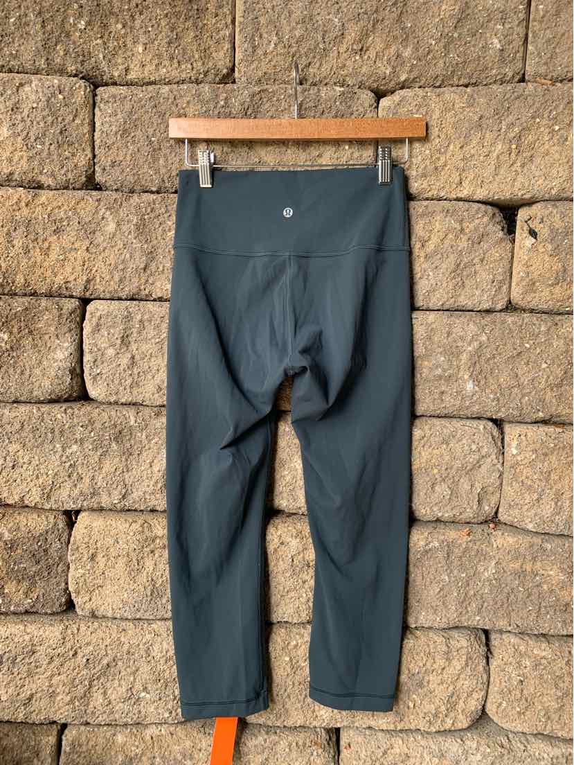 Teal cropped athletic leggings with high waistband and Lululemon logo on back.