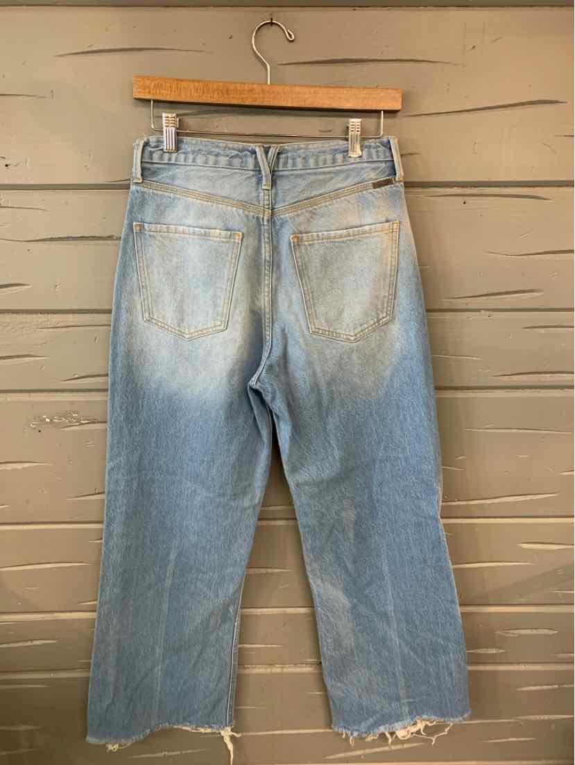 Light blue denim wide-leg jeans in size 7 with distressed faded details and frayed hems hanging on wooden hanger.