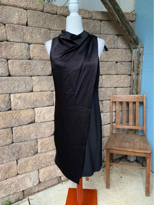 Sleeveless black midi dress with draped cowl neck and asymmetrical hem on mannequin.