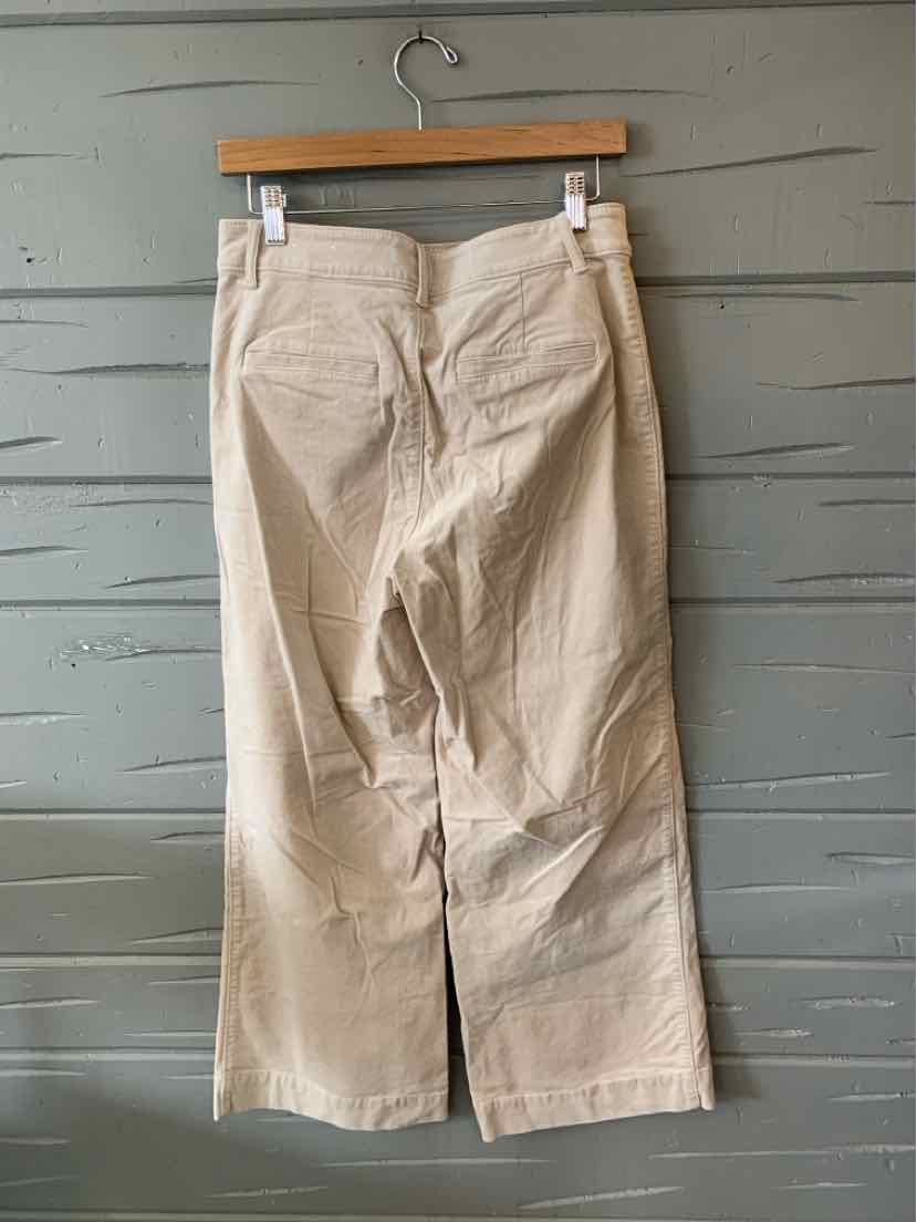 Tan wide-leg pants in size 6P with visible back pockets and belt loops, hanging on wooden hanger.
