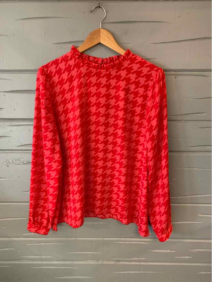 Red houndstooth long-sleeve blouse with round neckline and relaxed fit on wooden hanger.