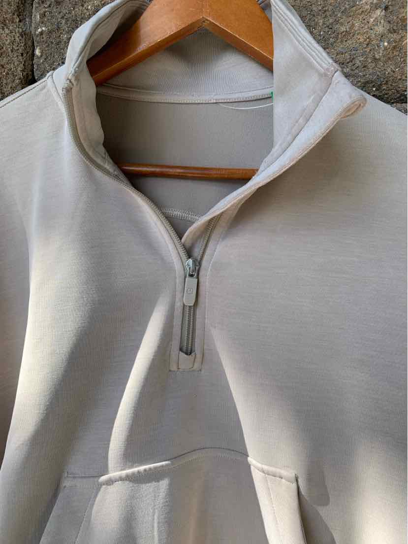 Tan half-zip pullover with a high collar and kangaroo pocket, made from soft fabric.