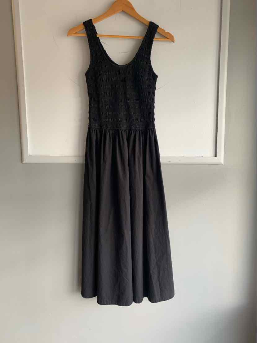 Black sleeveless midi dress with textured fitted bodice and flowing skirt on wooden hanger.