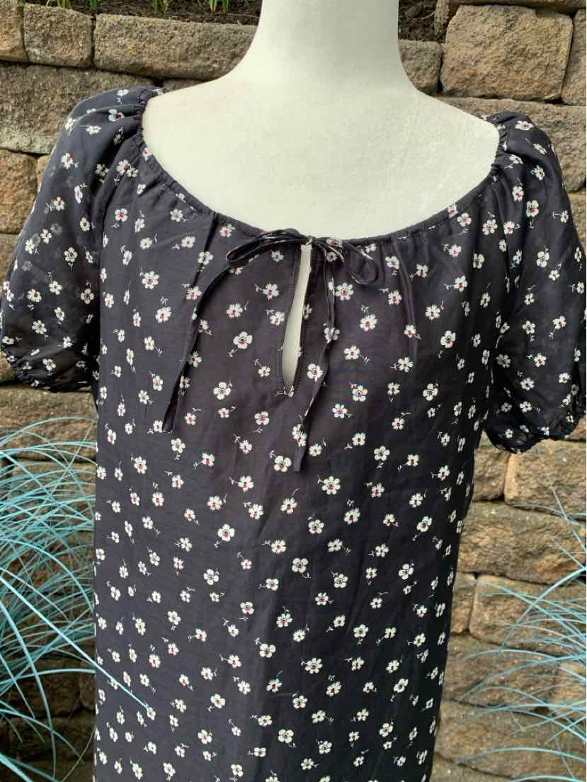 Black floral dress with white daisies, puff sleeves, and a small front tie neckline.