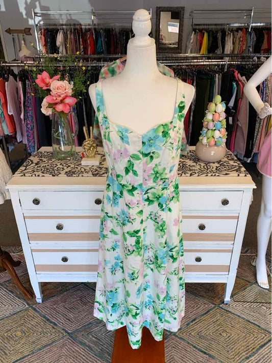 White floral sleeveless midi dress with green and pink flower print, fitted bodice and flowing skirt.
