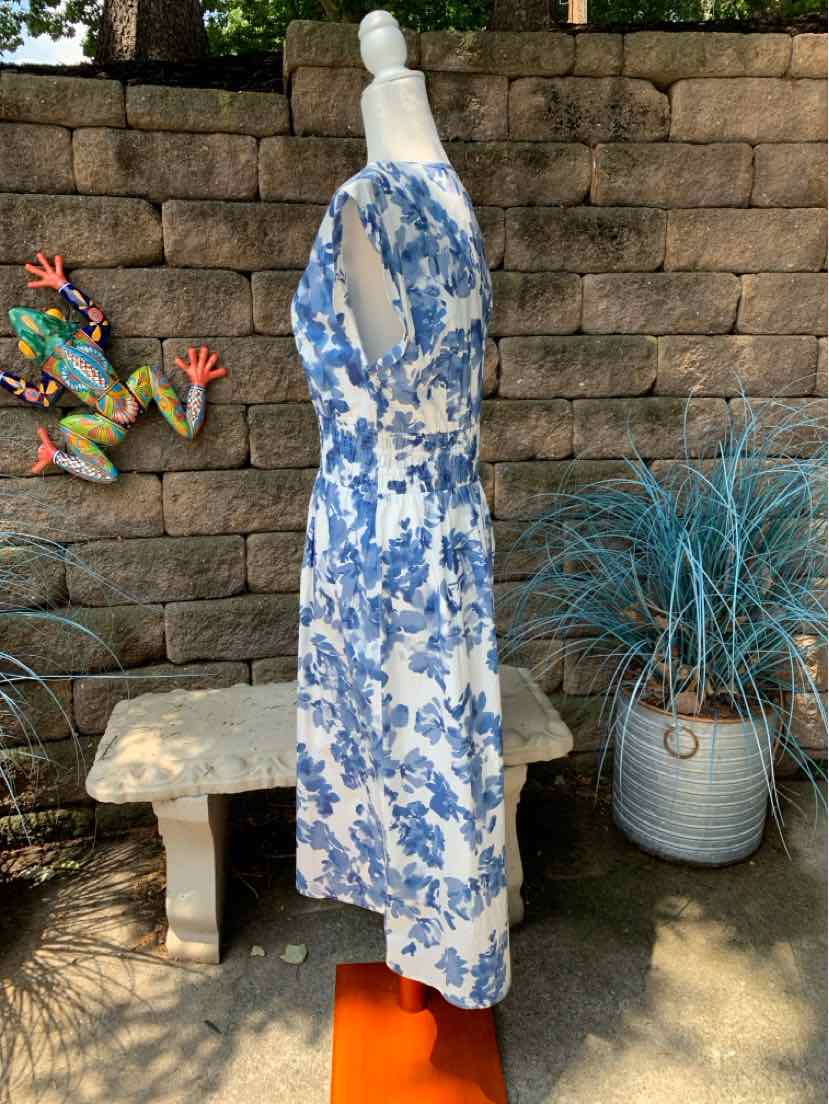 Sleeveless white dress with blue floral print and fitted waist on mannequin side view.