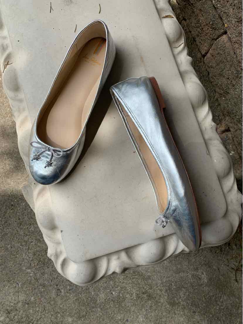 Metallic silver ballet flats with round toes and small decorative bows on top, size 9.5.