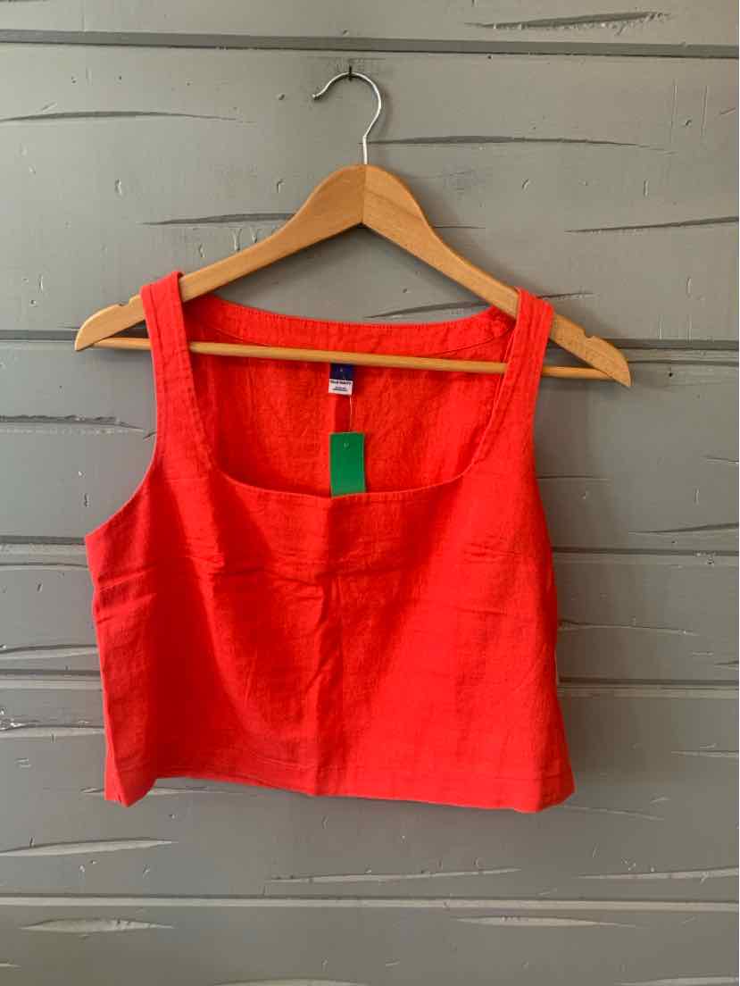 Red solid square-neck crop top with wide straps hanging on wooden hanger against gray wall.