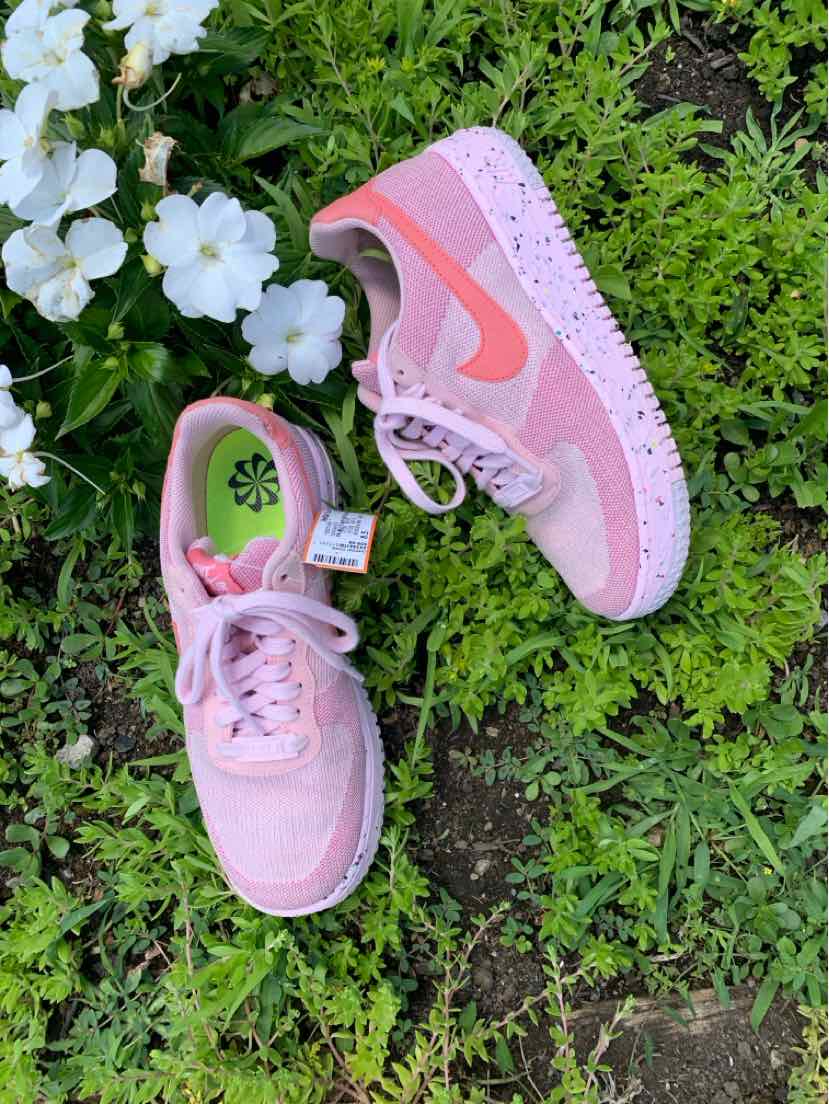 Pink Nike sneakers with pastel orange swoosh, speckled sole, and mesh upper, size 8.5.