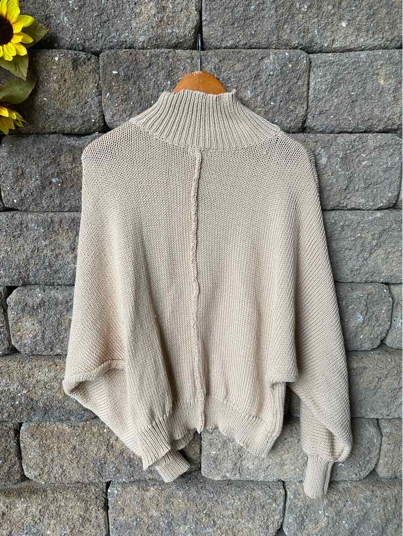 Tan knitted turtleneck sweater with loose, oversized silhouette and ribbed cuffs and hem.