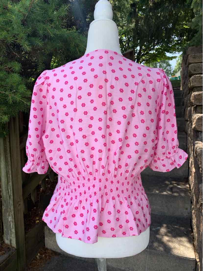 Pink blouse with dark pink polka dots, cinched waist, and short puff sleeves.