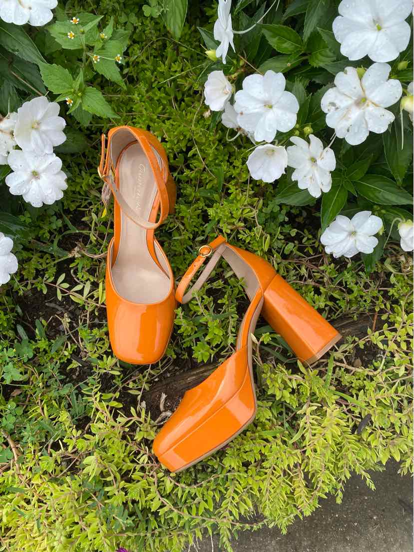 Orange leather block heel shoes with closed square toe and ankle strap buckle fastening.