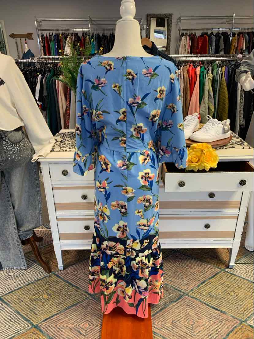 Blue long floral dress with pink trim and gathered sleeves on mannequin in boutique.