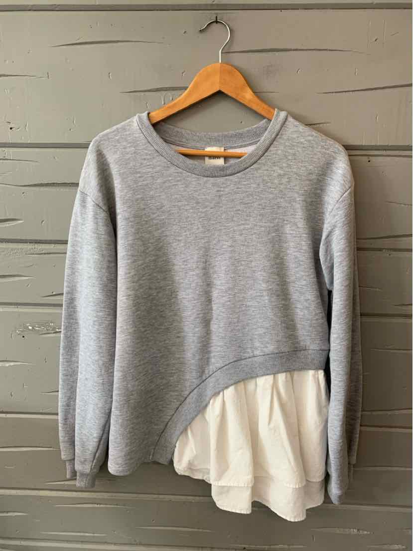 Gray long-sleeve sweatshirt with rounded neckline and attached white asymmetrical ruffle hem.
