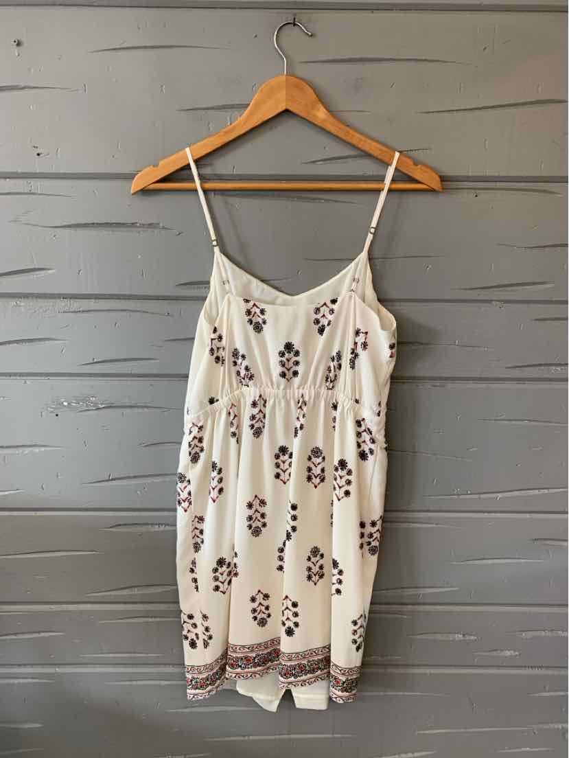 White sleeveless dress with thin straps, featuring a purple floral pattern and a decorative border along the hem.