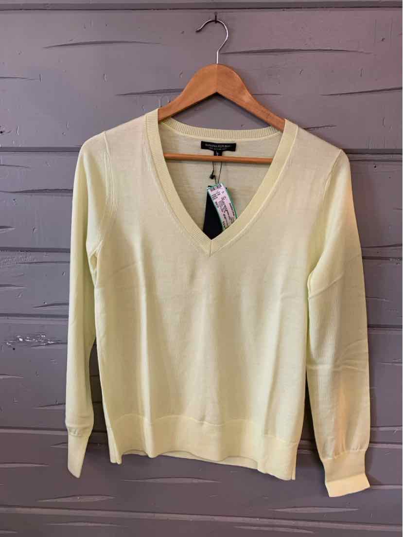 Light yellow V-neck long-sleeve sweater in medium size hanging on wooden hanger.