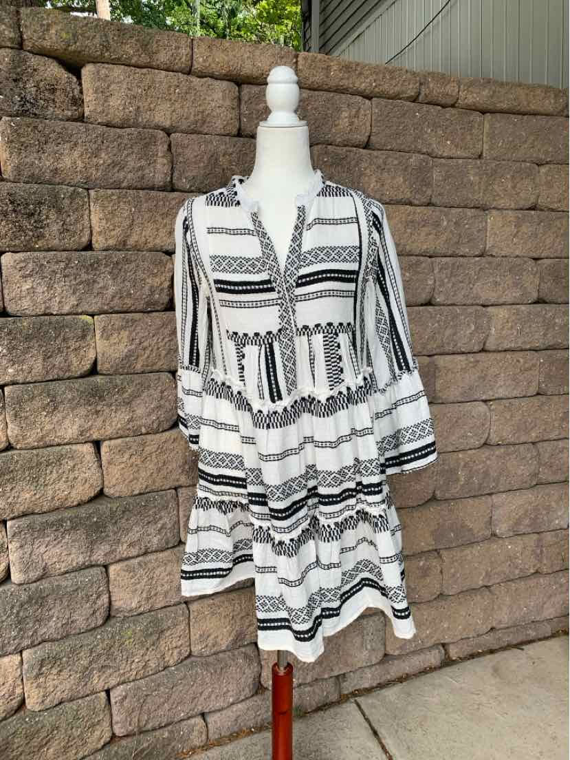 White and black embroidered long-sleeve mini dress with tiered skirt and V-neck tie closure.