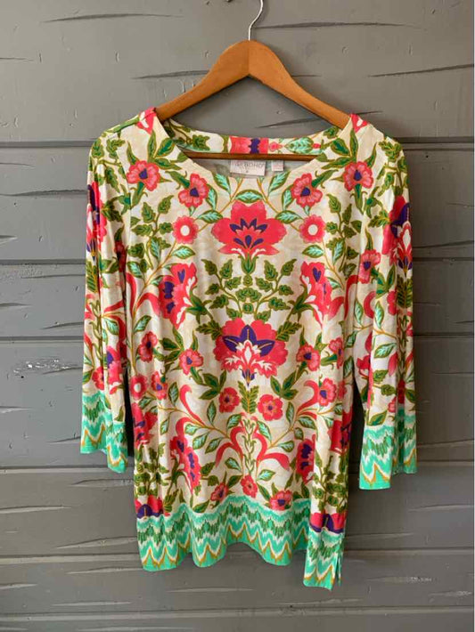 Long-sleeve boho blouse in cream with vibrant pink, green, and blue floral print and turquoise zigzag hem.
