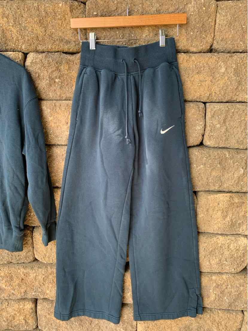 Dark blue Nike sweatpants with elastic waistband, drawstring, wide legs, and white Nike swoosh logo on left thigh.