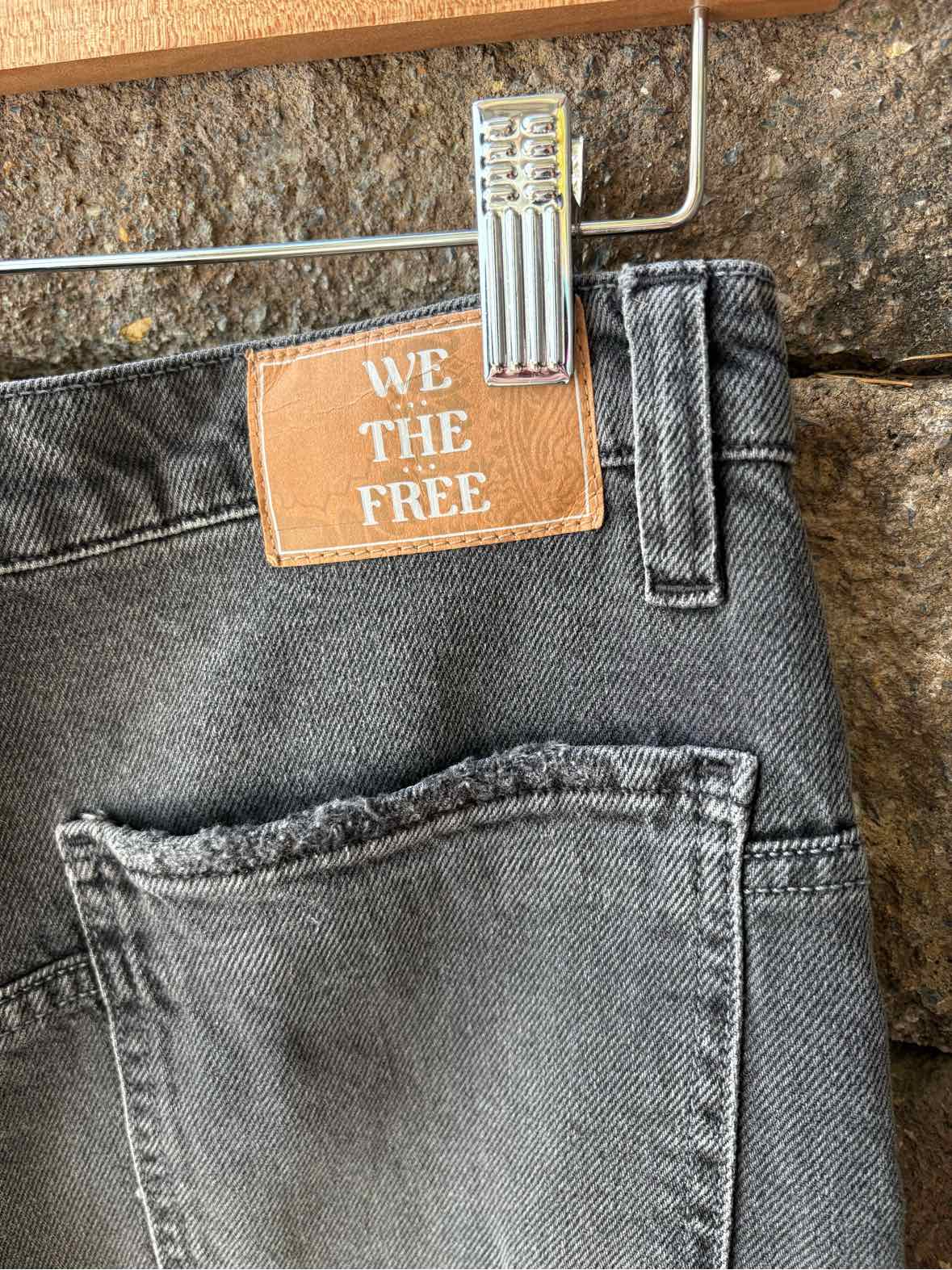 Black washed denim jeans with a back pocket, belt loop, and tan We The Free tag.