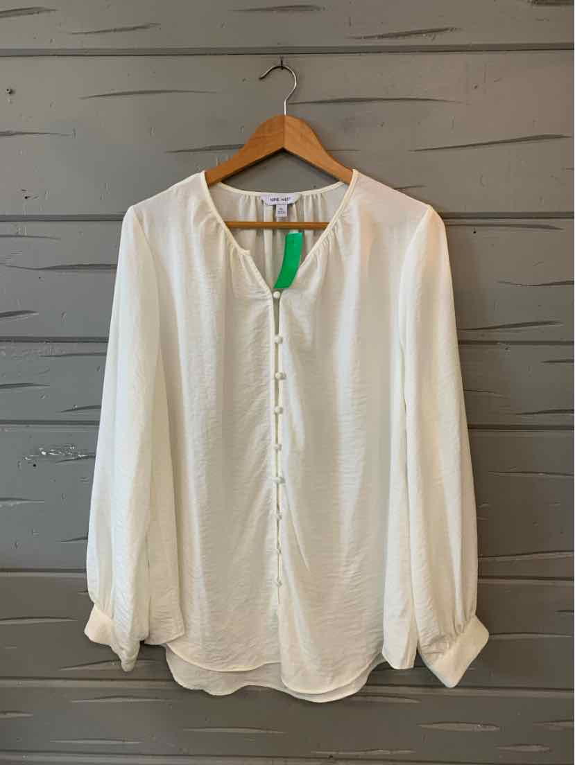 White long-sleeve blouse with round neckline, front button placket, and relaxed fit hanging on wooden hanger.