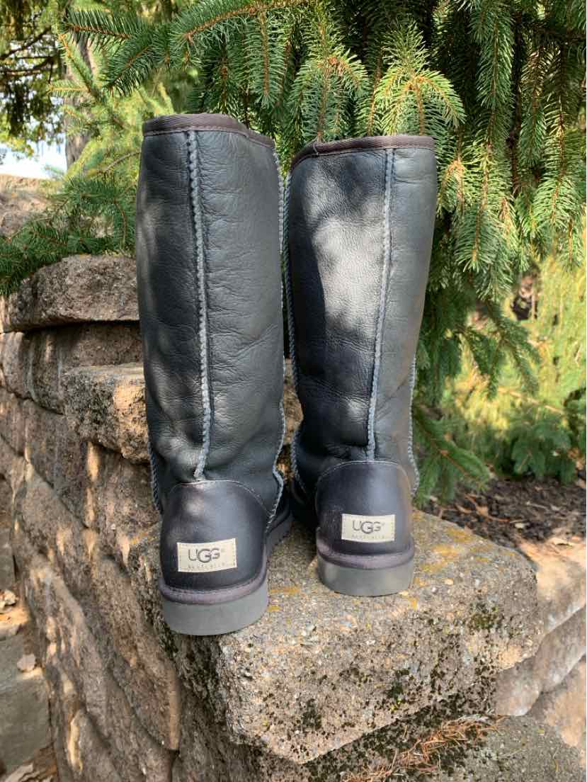 Pair of charcoal gray UGG boots with tall suede shafts, plush lining, and logo heel patches.