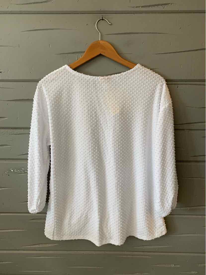 White textured long-sleeve blouse with scoop neckline and slightly curved hem on wooden hanger.