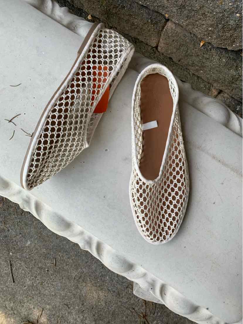 Beige slip-on shoe with open woven mesh design, rounded toe, and flat sole.