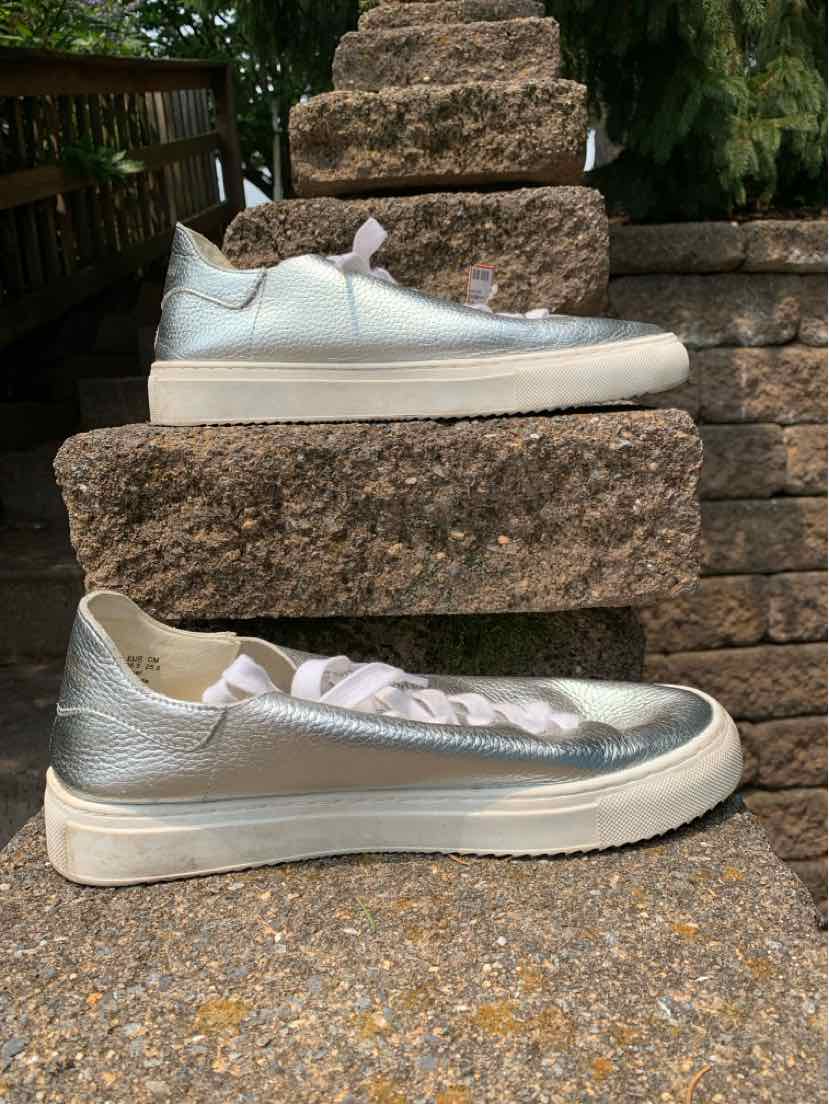 Metallic silver low-top sneaker with white sole and laces, sleek leather upper, size 8.5.