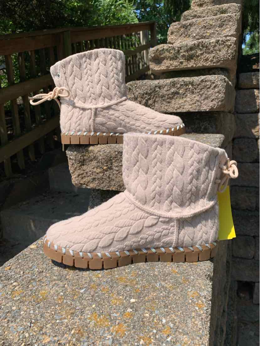 Beige ankle boots with cable knit texture, flat rubber sole, and drawstring detail at heel.