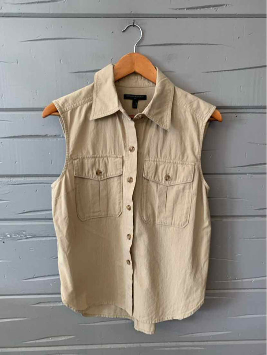 Sleeveless tan button-up shirt with front flap pockets and a classic collar hanging on wooden hanger.