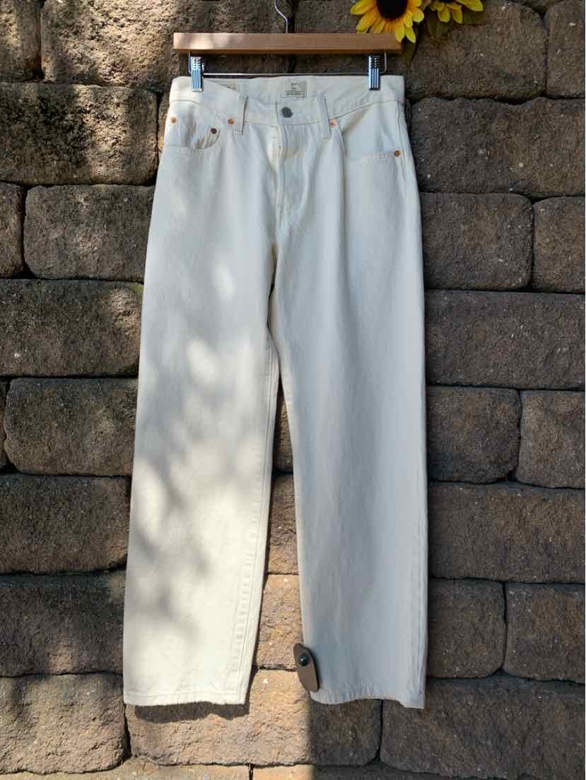 High-waisted white denim jeans with straight legs and classic five-pocket design hanging on wooden hanger.