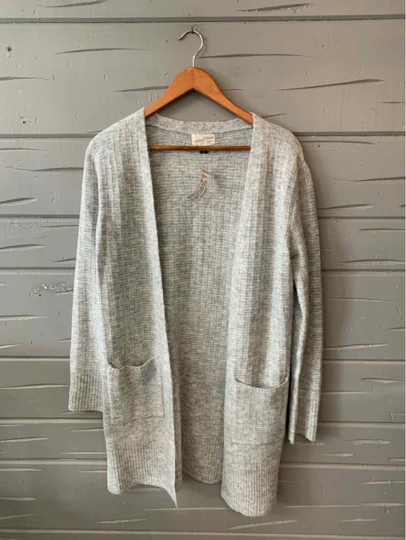 Light gray open-front knit cardigan with long sleeves and front pockets hanging on wooden hanger.