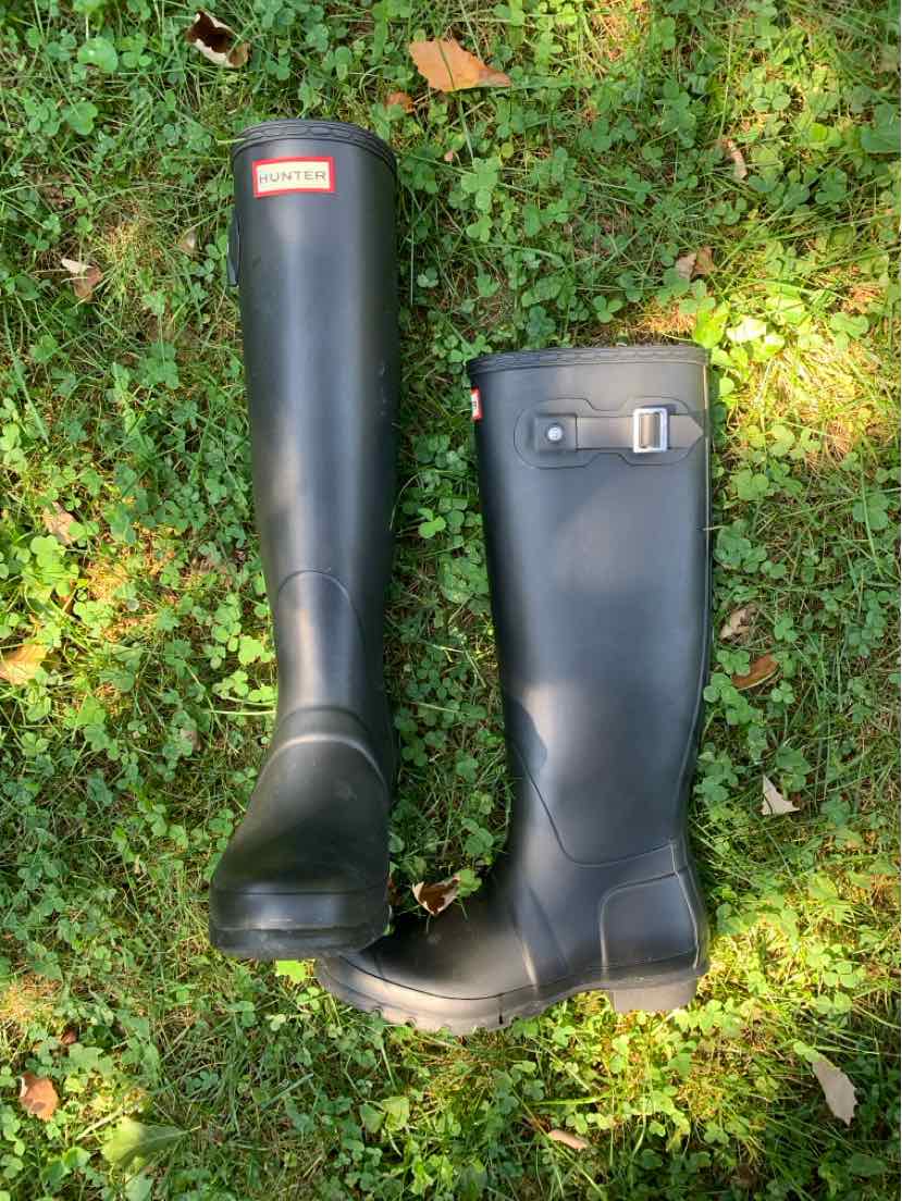 Tall black rubber rain boots with adjustable side buckle and red logo on the front top.