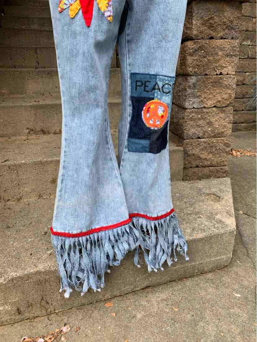 Light blue denim bell-bottom jeans with fringe hem, red stitching, and colorful patchwork on leg.