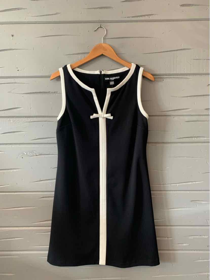 Black sleeveless dress with white trim and a white bow accent at the front center.