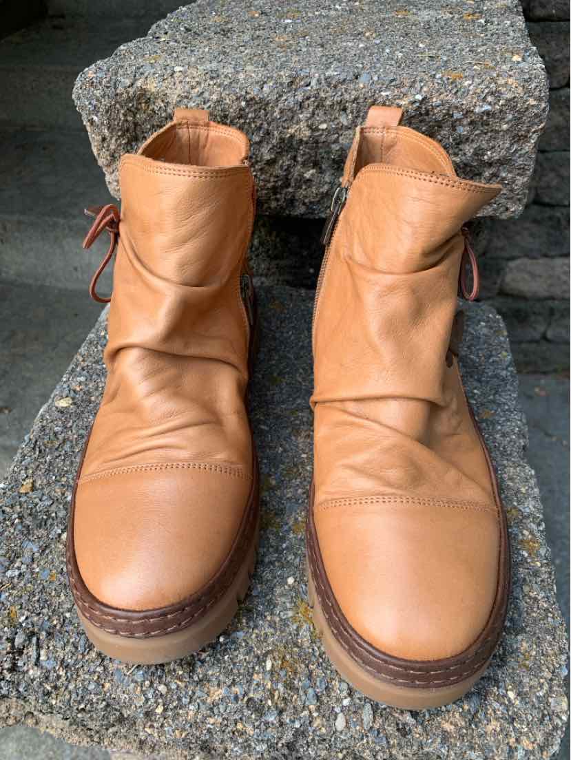Tan leather ankle boots with rounded toes, stitched details, and side zipper closures.
